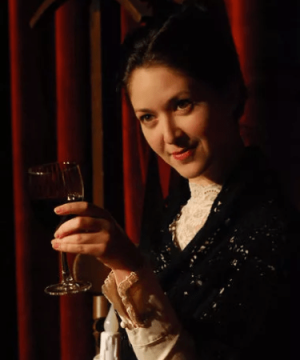 An woman holds a glass of red wine for the play The Unfortunates for TRW Plays