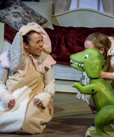 A woman dressed as a rabbit is talking to a dinosaur puppet.